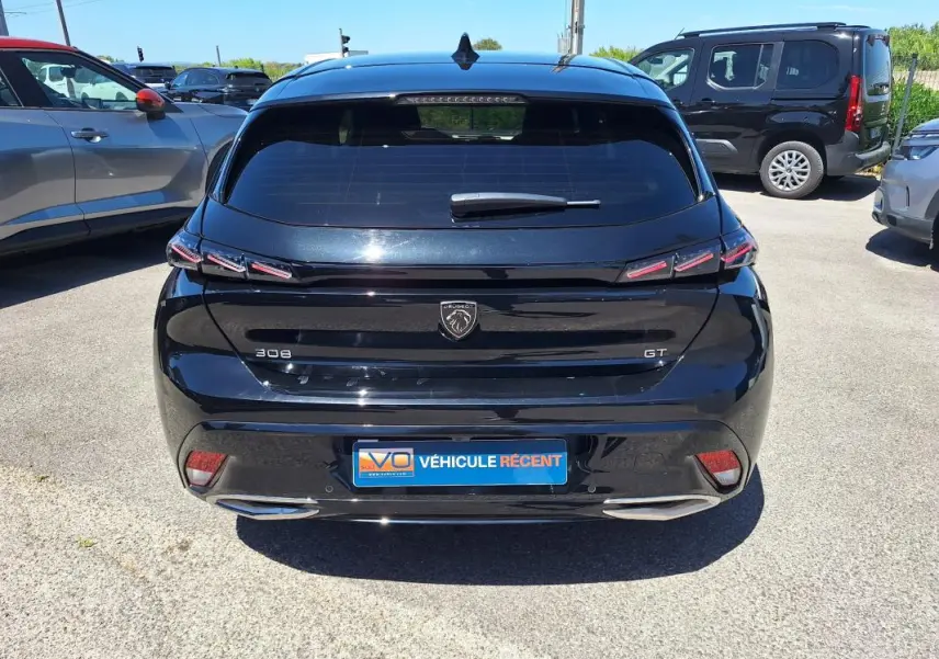 Vue arrière d'une Peugeot 308 Hybrid 145 e-DCS6 GT noire avec feux LED et double sortie d'échappement chromée.