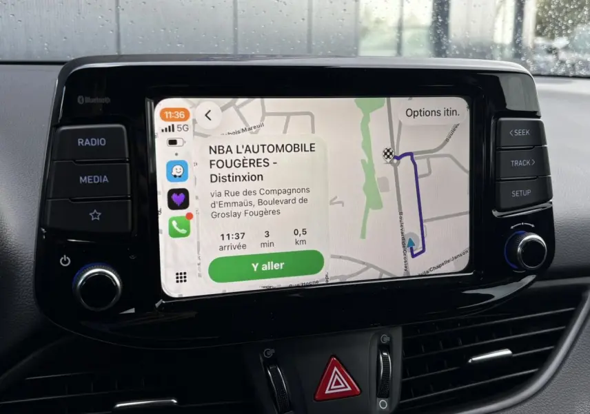 Écran tactile central de la Hyundai i30 SW T-GDI 120 Modern affichant un GPS avec itinéraire, boutons de contrôle autour.