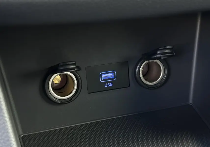 Vue rapprochée du port USB et des deux prises 12V avec couvercles ouverts dans l’habitacle d’une Hyundai i30 SW gris argent.