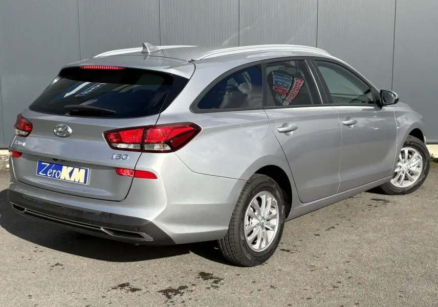Vue 3/4 arrière droite d'une Hyundai i30 SW T-GDI 120 Modern gris argent métallisé avec jantes alliage et vitres arrière surteintées.