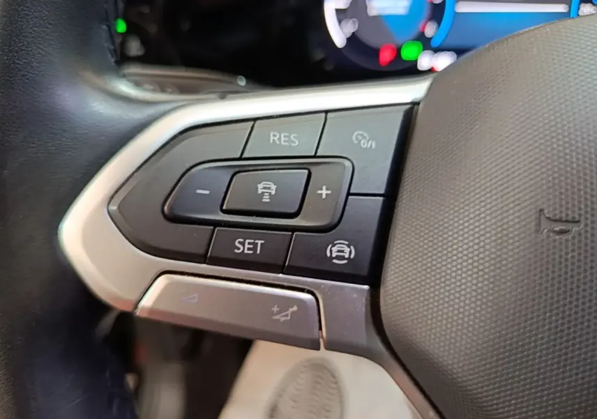 Gros plan sur les commandes du volant côté gauche de la Volkswagen Golf noire 2023 avec affichage digital en arrière-plan.