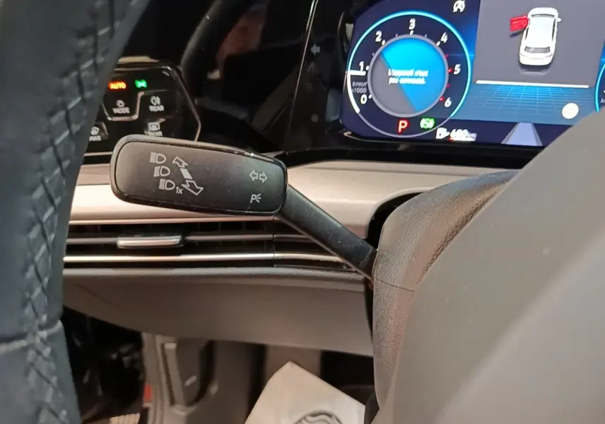 Gros plan intérieur sur le commodo gauche et tableau de bord numérique bleu de la Volkswagen Golf noire 2023.