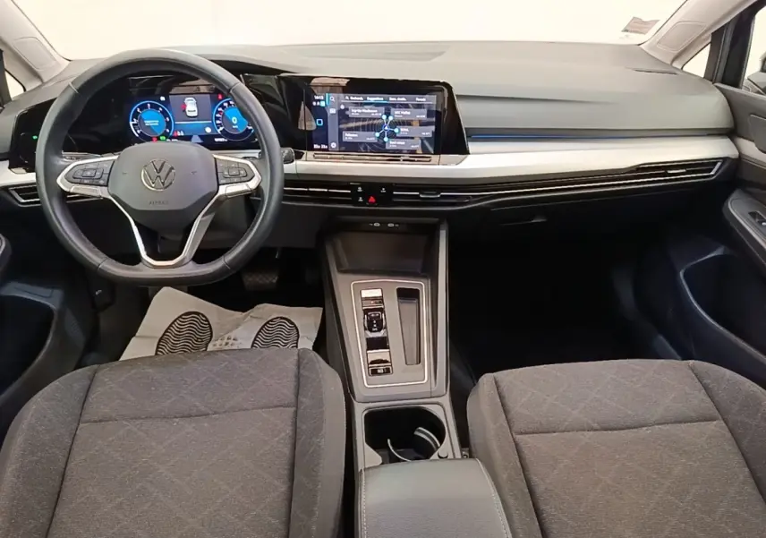 Vue intérieure avant de la Volkswagen Golf 2023 noire, tableau de bord digital et écran tactile central lumineux.