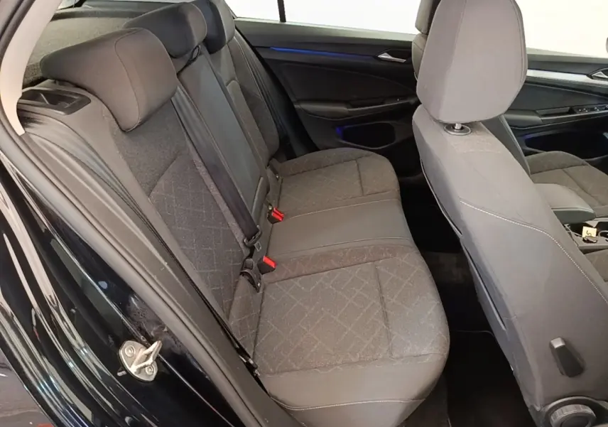 Vue intérieure côté gauche montrant la banquette arrière grise et les sièges avant d'une Volkswagen Golf noire 2023.