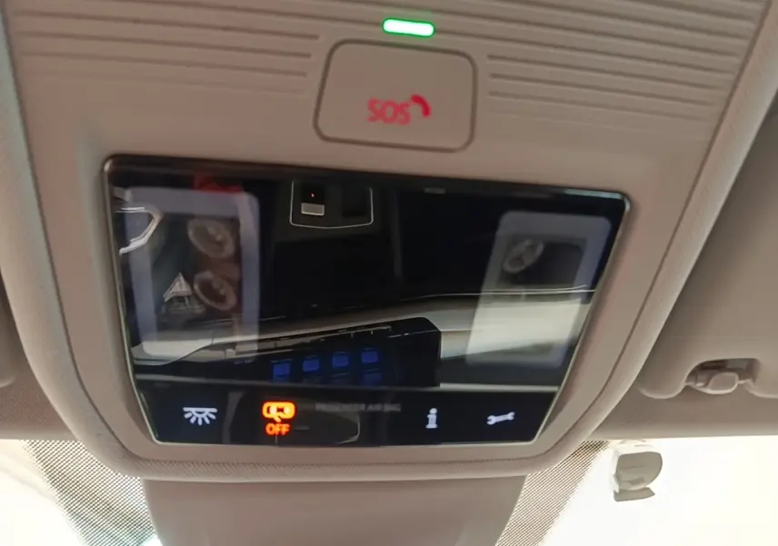 Vue en gros plan du panneau de commandes au plafond intérieur de la Volkswagen Golf noire 2023, avec bouton SOS et éclairage ambiant.