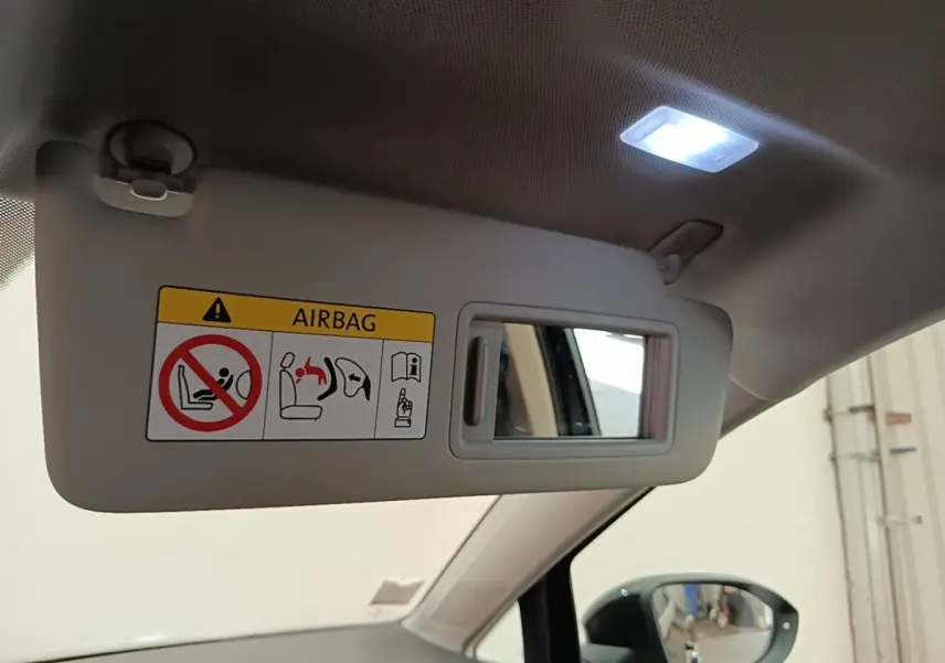 Détail du pare-soleil côté conducteur beige avec miroir et avertissement airbag, intérieur clair d'une Volkswagen Golf noire.