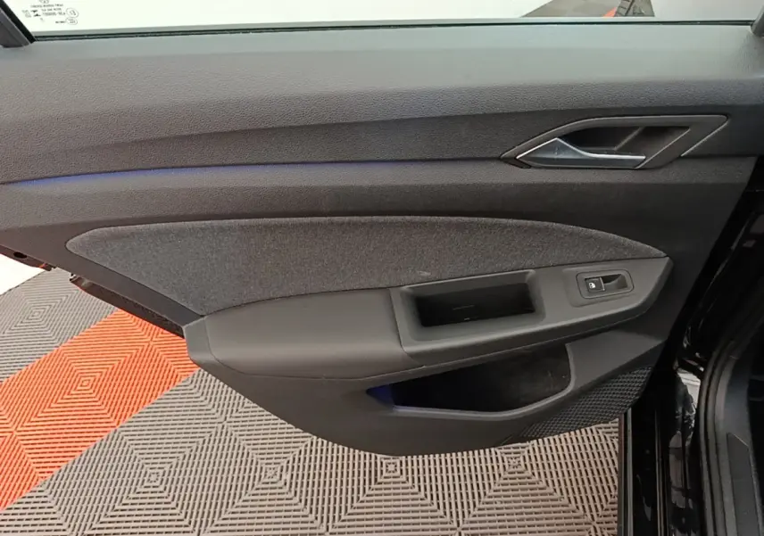 Vue intérieure de la porte côté conducteur d'une Volkswagen Golf noire 2023, avec habillage tissu et plastique noir.