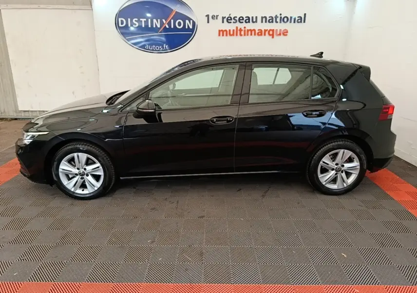 Profil droit d'une Volkswagen Golf noire 2023, en intérieur avec logo Distinxion en arrière-plan.