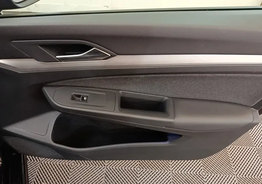 Vue intérieure du panneau de porte côté gauche noir de la Volkswagen Golf 2.0 TDI 2023 avec poignée argentée.