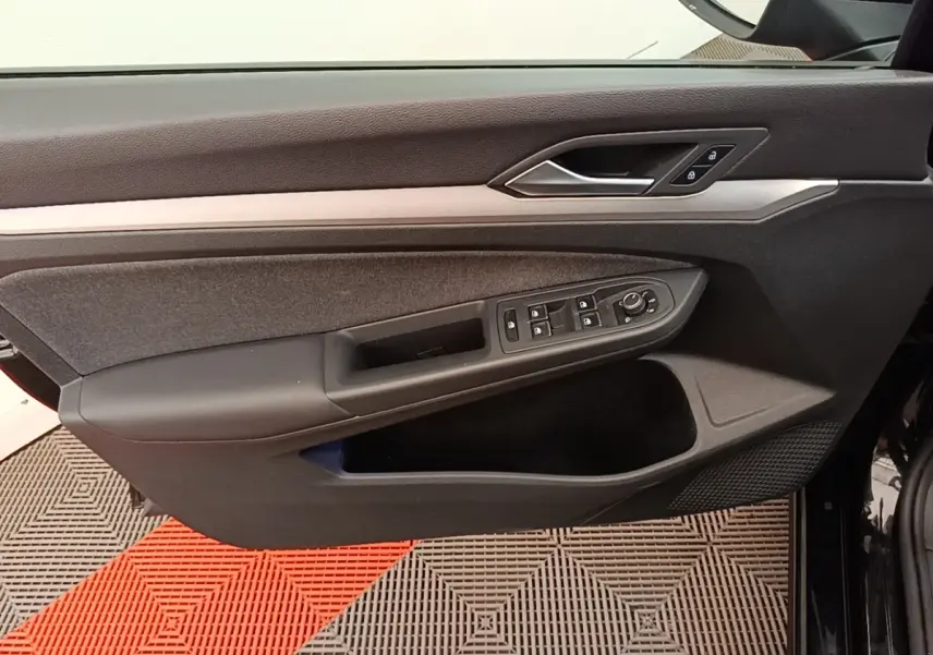 Vue rapprochée de la porte côté conducteur noire de la Volkswagen Golf 2023 avec commandes des vitres et verrouillage.