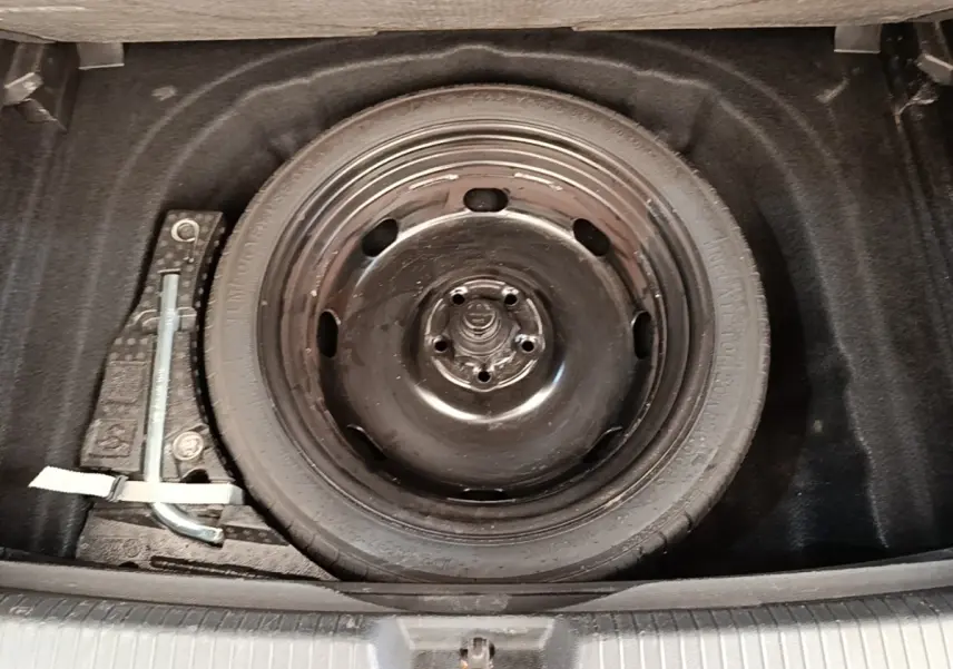 Vue rapprochée de la roue de secours galette noire dans le coffre d'une Volkswagen Golf 2023.