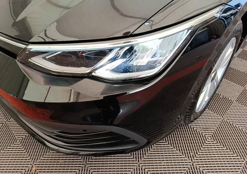 Gros plan sur le phare avant droit de la Volkswagen Golf noire 2023, mettant en valeur son design LED moderne.