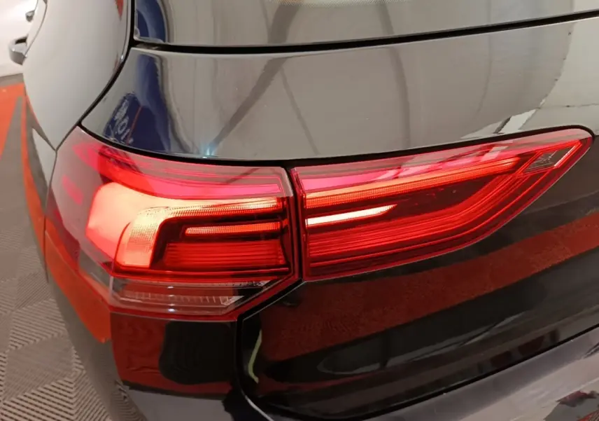 Gros plan sur le feu arrière gauche rouge d'une Volkswagen Golf noire 2023, vue depuis l'arrière côté gauche.
