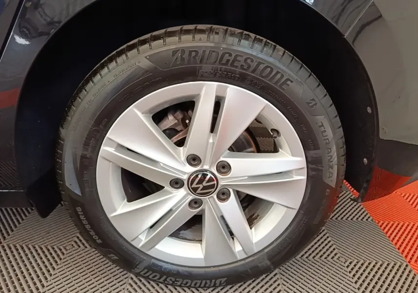 Gros plan sur la roue avant droite d'une Volkswagen Golf noire avec jante alliage argent et pneu Bridgestone.