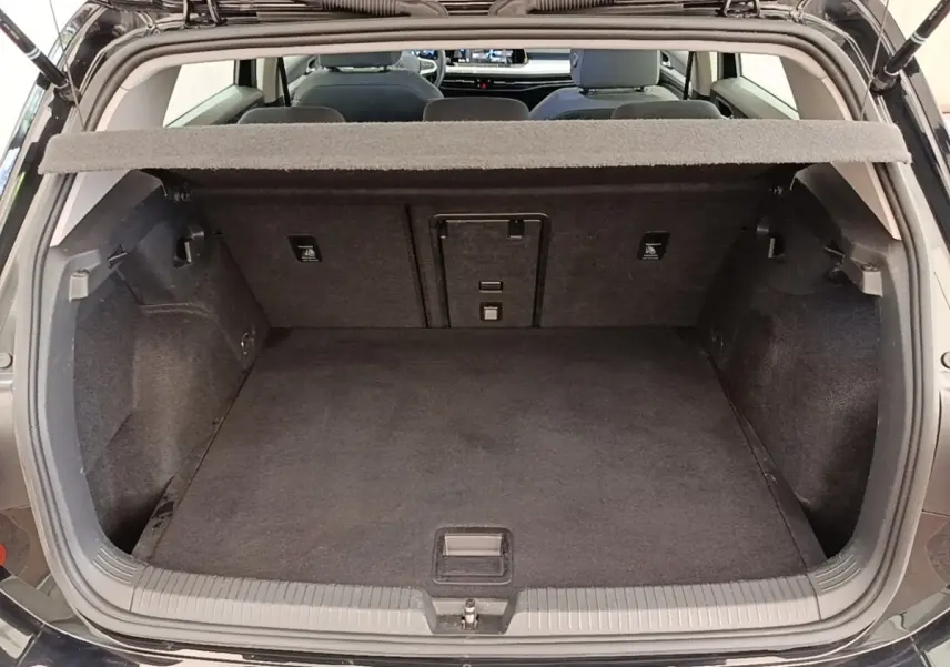 Vue arrière du coffre ouvert d’une Volkswagen Golf noire 2023, montrant l’espace de chargement vide et la tablette cache-bagages.