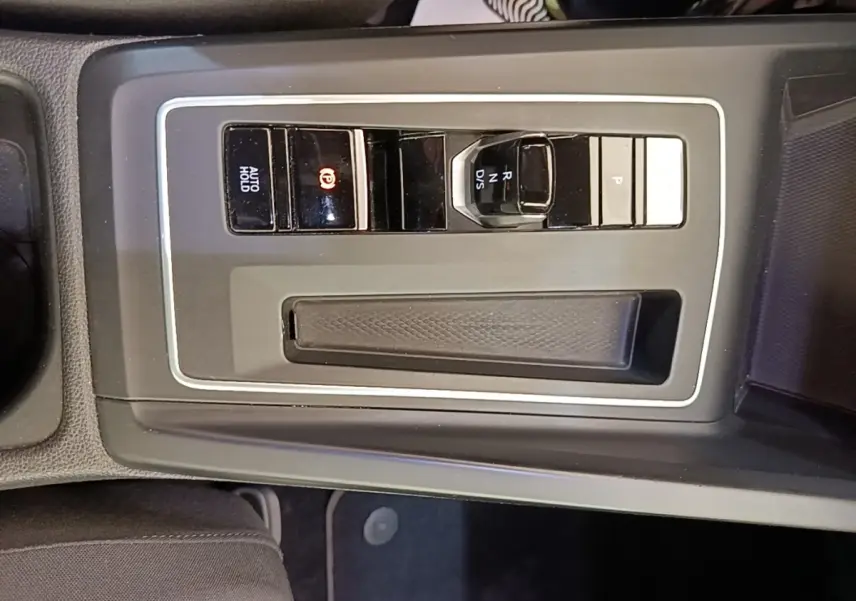 Vue plongeante sur la console centrale noire de la Volkswagen Golf 2023 avec boutons de frein à main électrique et sélecteur de vitesse.