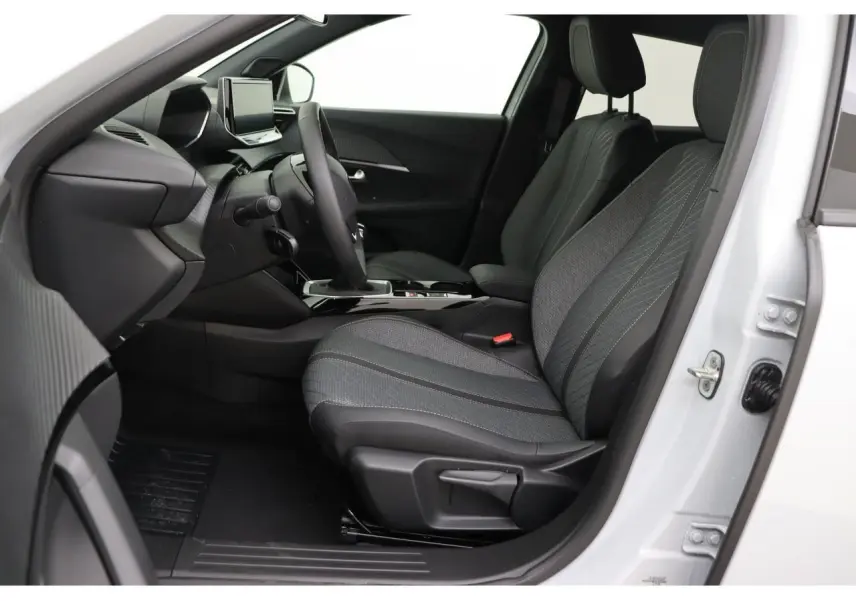 Vue intérieure côté conducteur du Peugeot 2008 blanc Okenite 2026, sièges tissu gris et tableau de bord moderne.