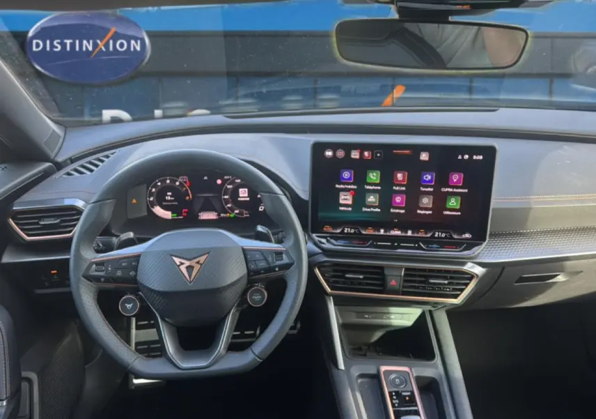 Vue intérieure frontale du tableau de bord et volant cuir du CUPRA Formentor 1.5 ETSI Hybrid avec écran tactile et finitions orange.