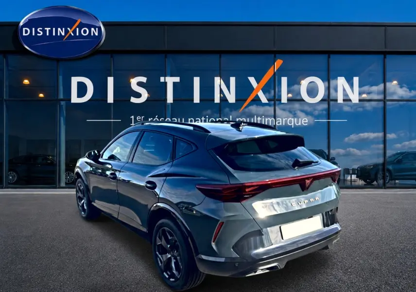 Vue 3/4 arrière droite du CUPRA Formentor bleu fjord 2026 avec feux arrière LED et jantes 18 pouces devant un showroom Distinxion.
