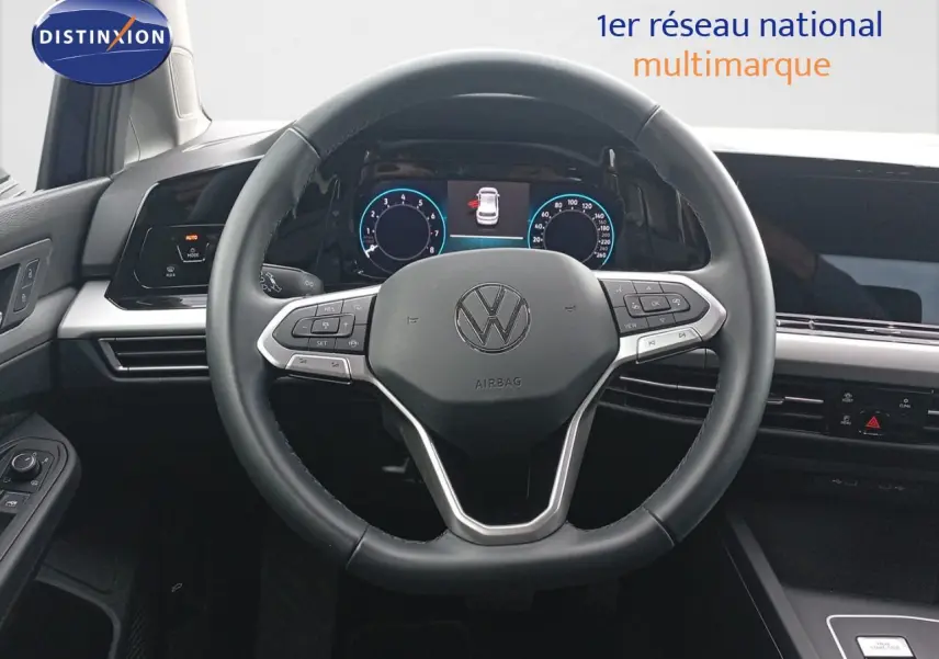 Vue intérieure centrée sur le volant multifonction noir de la Volkswagen Golf VIII 2023 avec tableau de bord digital.
