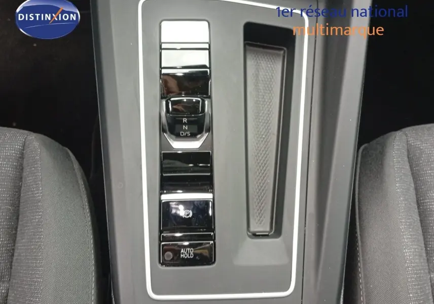 Vue en plongée sur la console centrale de la Volkswagen Golf VIII avec levier de vitesses automatique et sièges gris.