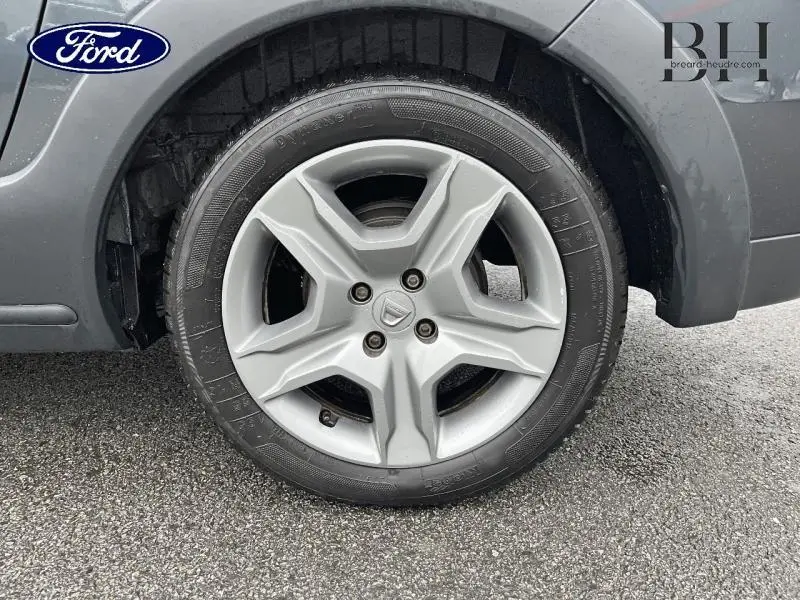 Gros plan sur la roue arrière droite d'un Dacia Lodgy gris Comète, avec passage de roue et partie de la carrosserie visible.