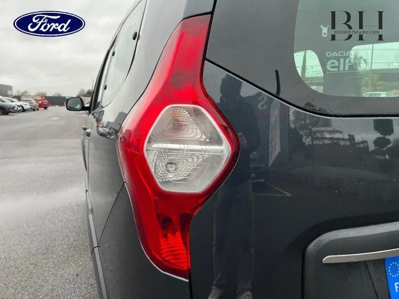 Gros plan sur le feu arrière droit gris Comète d'un Dacia Lodgy 2020, avec reflet et arrière-plan parking.