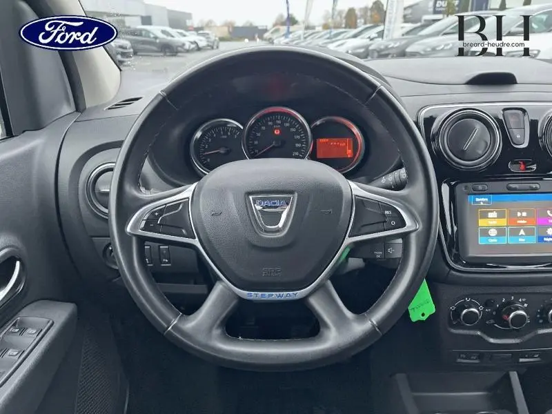 Vue intérieure centrée sur le volant noir Dacia Stepway avec tableau de bord et écran tactile visible.