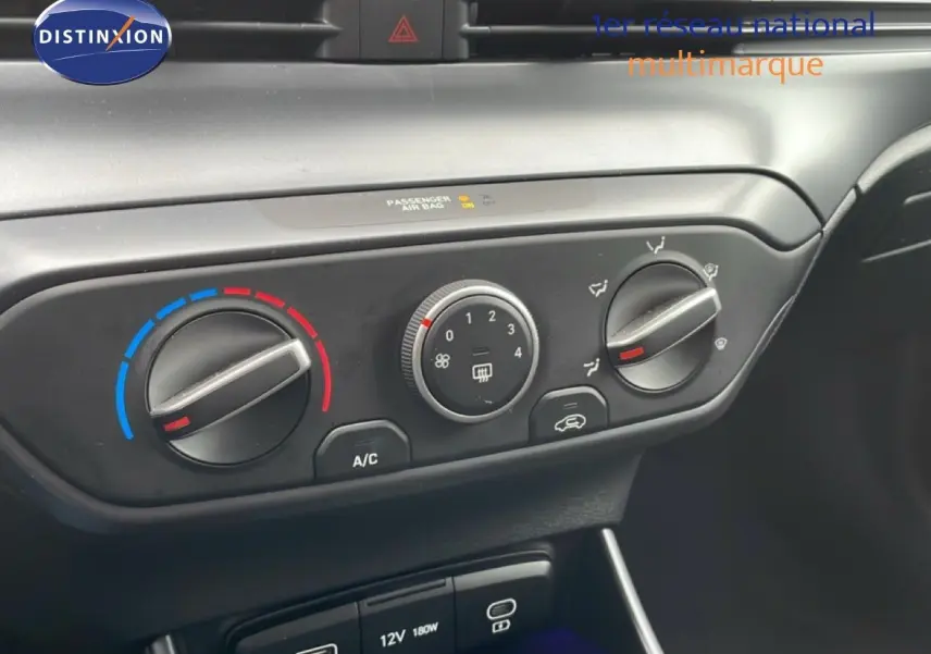 Gros plan sur les commandes de climatisation et prises USB dans l'habitacle noir du Hyundai i20 2025 vert Mangrove.