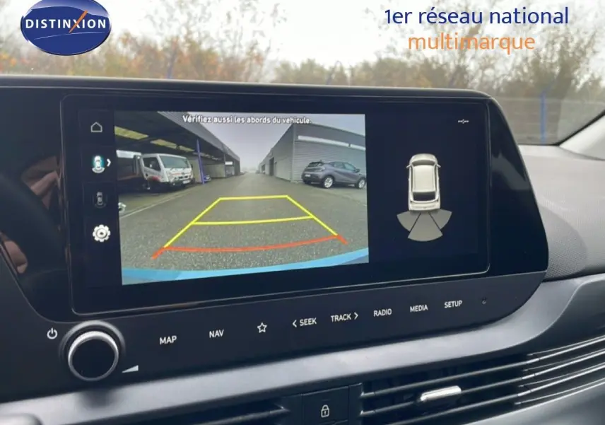 Écran central montrant la caméra de recul d'une Hyundai i20 2025, avec vue arrière et aides au stationnement.