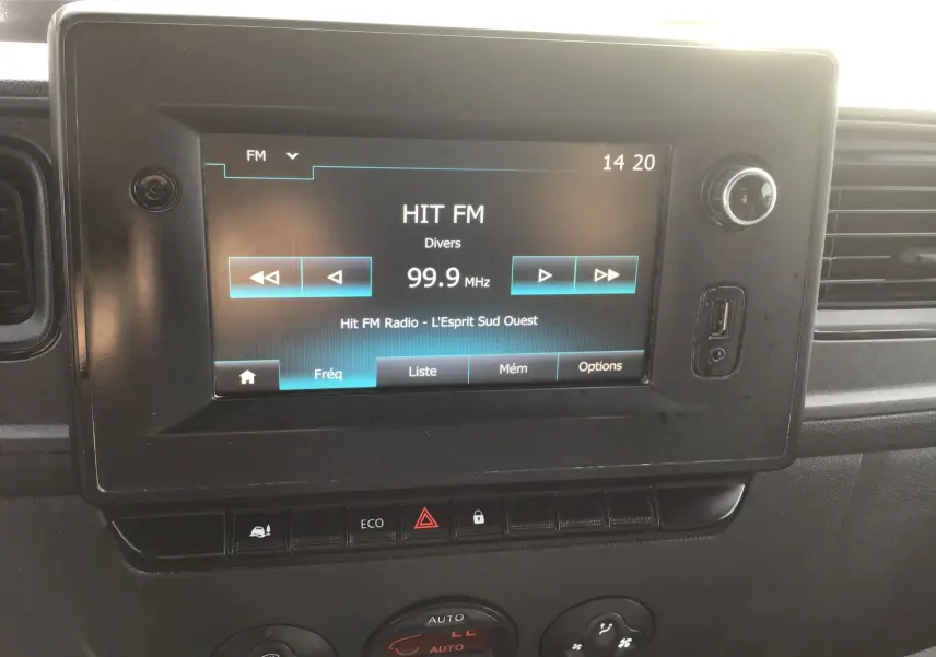Gros plan sur l’écran tactile central du Renault Master blanc, affichant la radio FM à 99,9 MHz avec commandes visibles.