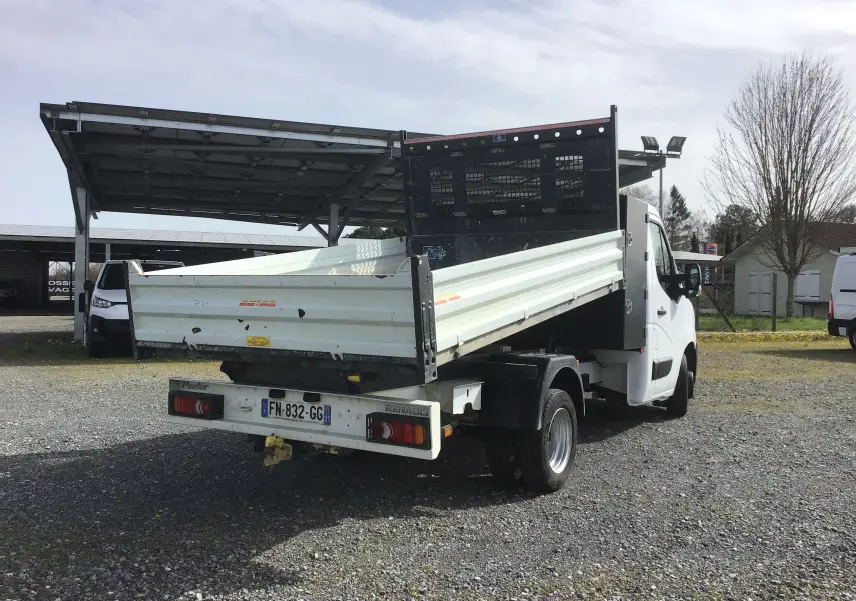 Renault Master Châssis cabine blanc vu 3/4 arrière droit, avec benne relevée et grille de protection noire.