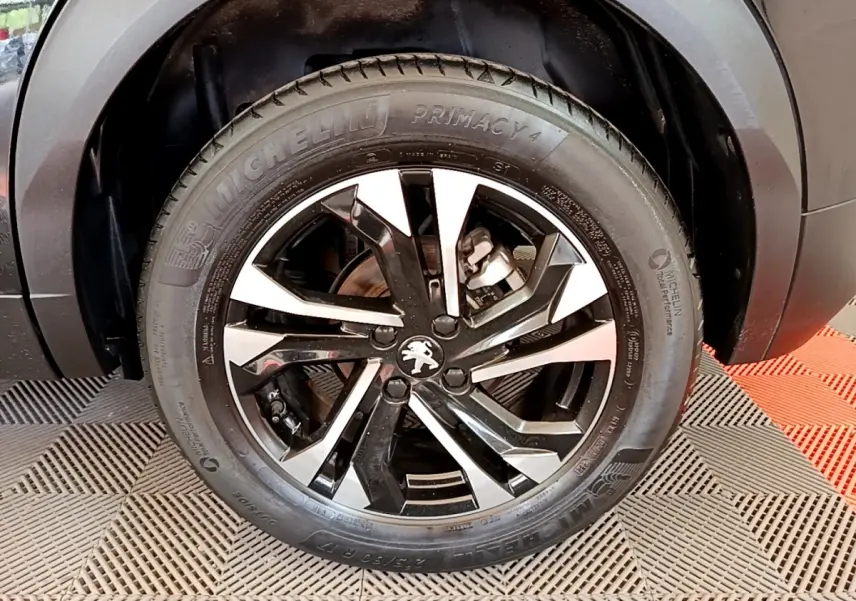 Gros plan sur la roue avant droite noire d’un Peugeot 2008 2021 avec jante alliage bicolore et pneu Michelin.