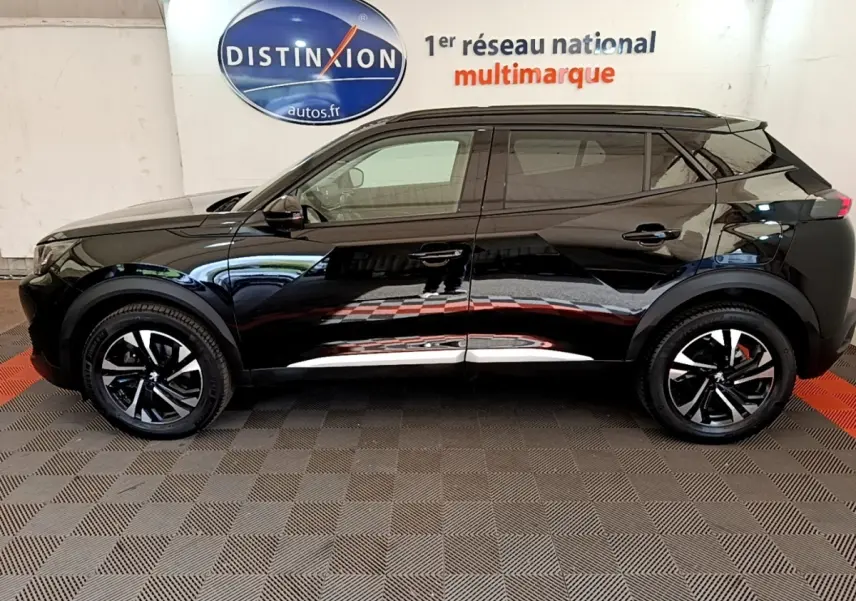 Profil côté gauche d’un Peugeot 2008 noir 2021 avec jantes noires et détails chromés, stationné en intérieur.