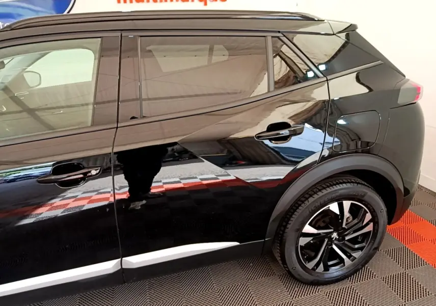 Profil droit noir brillant du Peugeot 2008 2021 avec jantes noires et détails de carrosserie modernes.