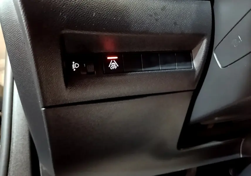Détail intérieur du tableau de bord côté conducteur du Peugeot 2008 noir, bouton d'assistance à la conduite désactivée.