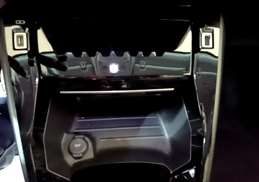 Gros plan sur la console centrale noire du Peugeot 2008 2021 avec prise 12V et finition brillante autour.