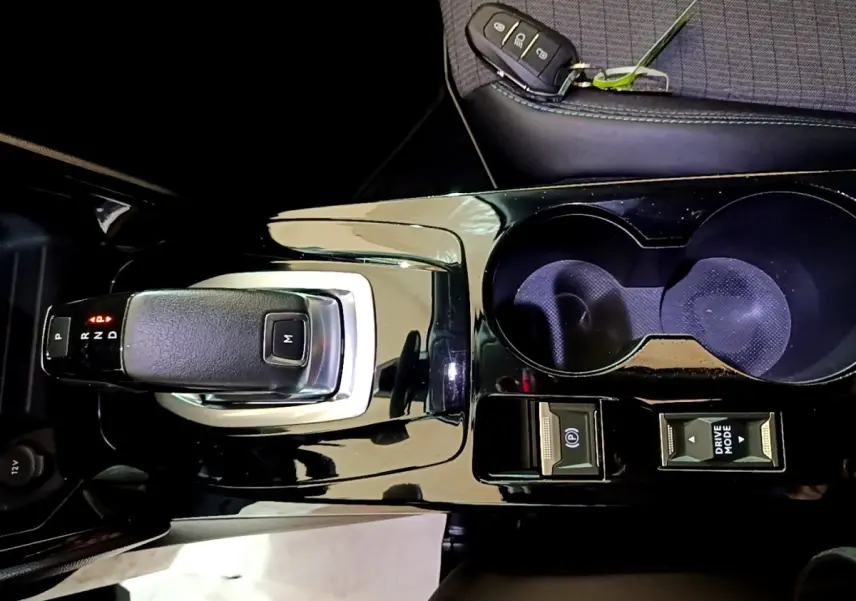 Vue rapprochée de la console centrale noire brillante de la Peugeot 2008 avec levier de boîte auto et porte-clés posé.