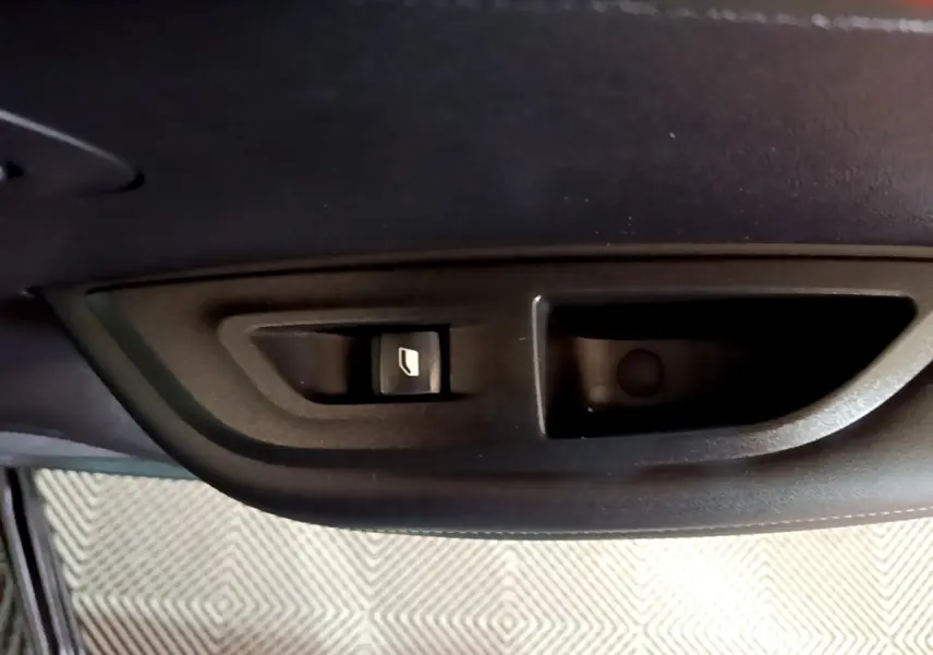 Gros plan sur la commande de lève-vitre côté porte intérieure d’une Peugeot 2008 noire, version 2021.