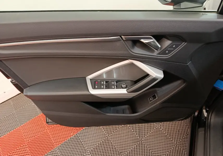 Porte avant gauche noire d’Audi Q3 Sportback 2023 avec commandes électriques et poignée argentée.
