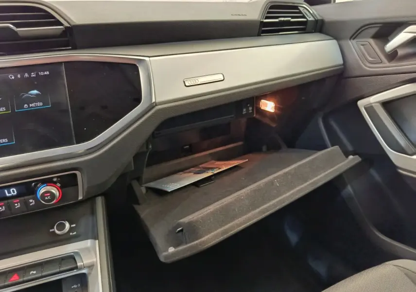 Intérieur de l'Audi Q3 Sportback 35 TDI 2023, vue côté passager avec boîte à gants ouverte et éclairage intérieur.