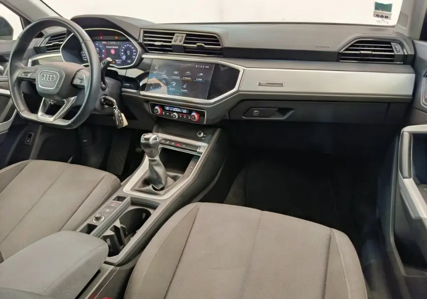 Intérieur avant de l'Audi Q3 Sportback noir 2023, vue du tableau de bord avec volant cuir et boîte manuelle.