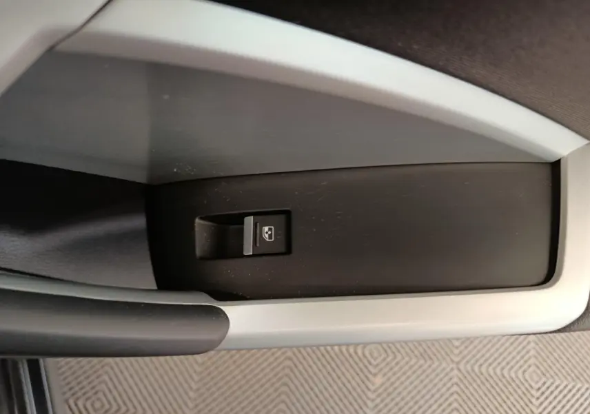 Gros plan sur le bouton de commande de lève-vitre dans l'accoudoir côté conducteur de l'Audi Q3 Sportback noir 2023.
