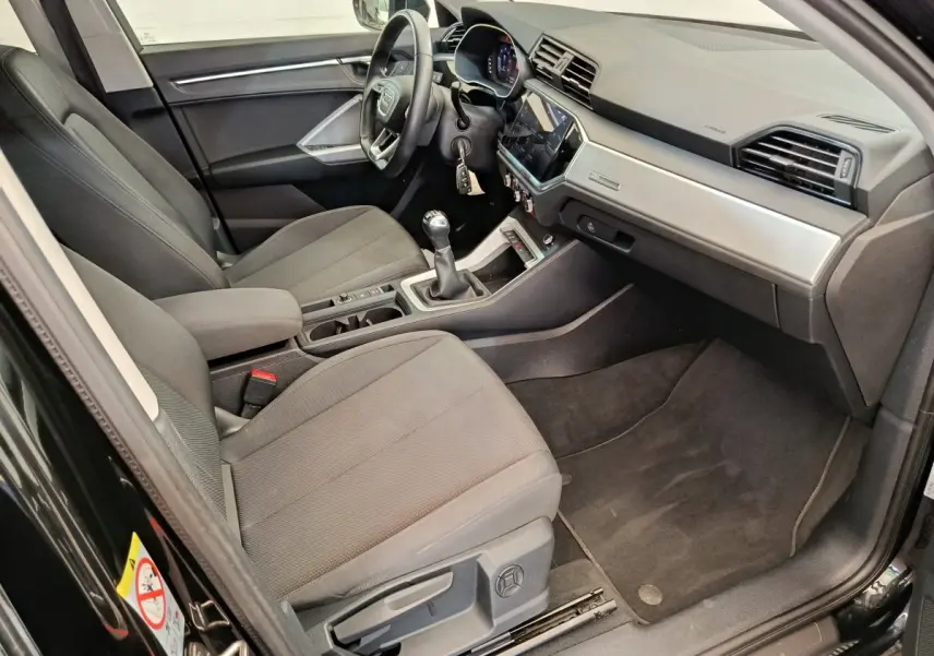 Vue intérieure côté conducteur de l'Audi Q3 Sportback 35 TDI 150 Business Line 2023 avec volant cuir et tableau de bord moderne.