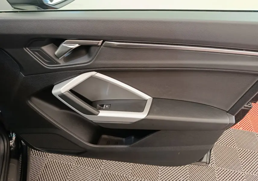 Vue intérieure de la porte avant gauche noire de l'Audi Q3 Sportback 35 TDI Business Line avec poignée argentée.