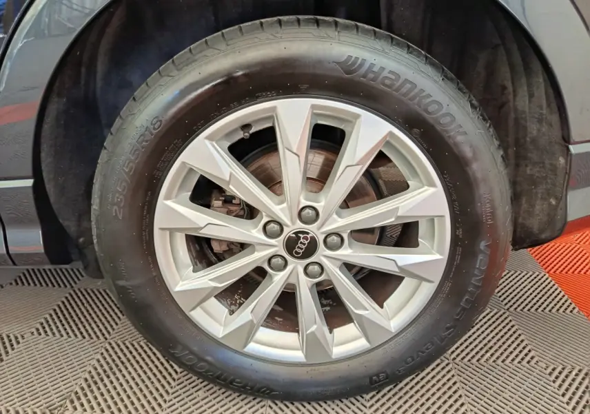 Gros plan sur la roue avant droite d’un Audi Q3 Sportback noir, jante alliage argentée à 10 branches.