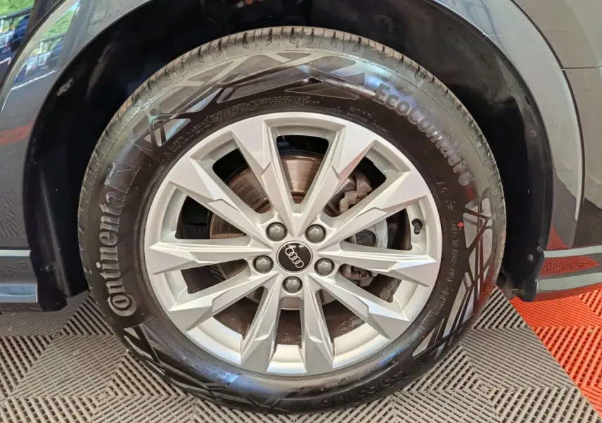 Gros plan sur la roue avant droite d’un Audi Q3 Sportback noir, jante alliage argentée et pneu Continental.