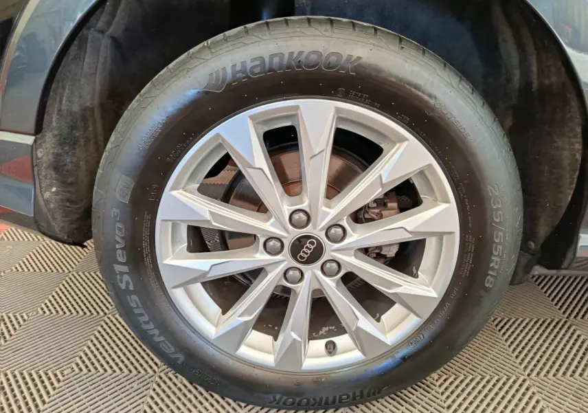 Gros plan sur la roue avant droite d’un Audi Q3 Sportback noir, avec jante alliage argent et pneu Hankook.