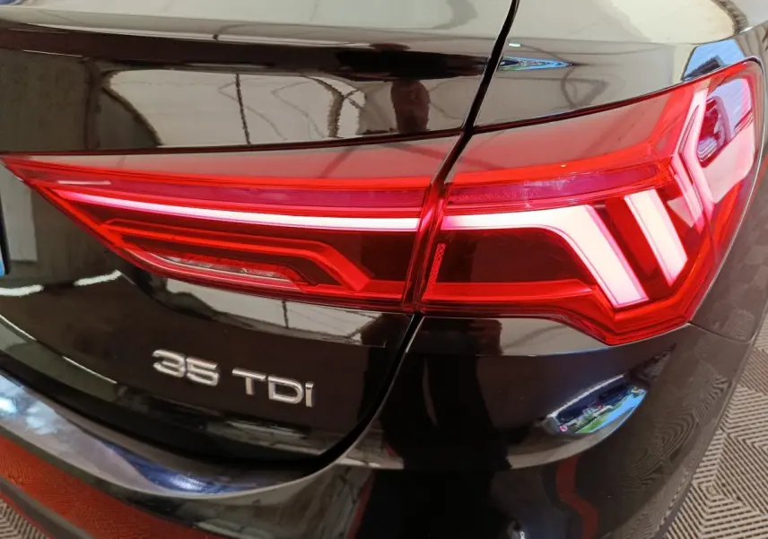 Gros plan sur le feu arrière droit rouge et le logo 35 TDI d’un Audi Q3 Sportback noir 2023.