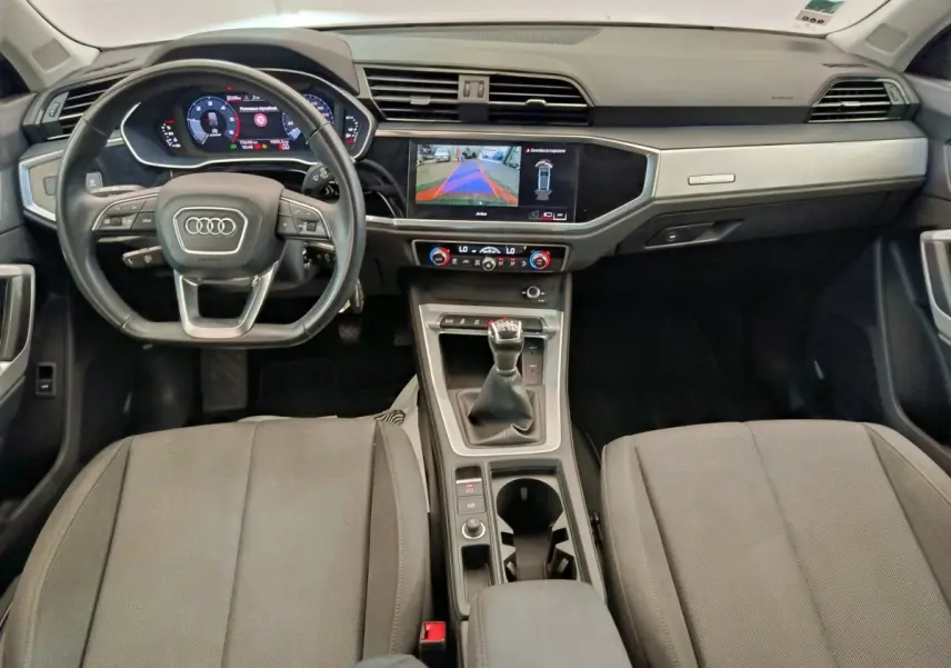 Vue intérieure avant de l’Audi Q3 Sportback 35 TDI Business Line 2023, volant cuir, écran tactile et levier de vitesse manuel.